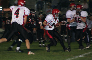 Brock Heath runs through a hole created by the line. At left is Devin Schmidt. #55 is Josh Roeper. Behind Roeper is David Johnson.