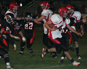 Devin Schmidt bursts through a hole in the line. Prairie players from left are David Johnson, Colton Nuxoll and Tim Frei.