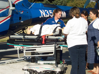 Faunda Butler, Respiratory Therapist and Sr. Janet Barnard watch as Life Flight staff load a pediatric manikin for transport by a Life Flight helicopter during a mock ER scenario.