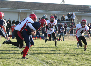 David Johnson takes a ride on a Lewis County runner before bringing him down. Also shown are Tim Frei and Devin Schmidt.