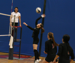 Megan Sigler spikes the ball in the Troy match. Also shown are MeShel Rad and Fran Johnson.