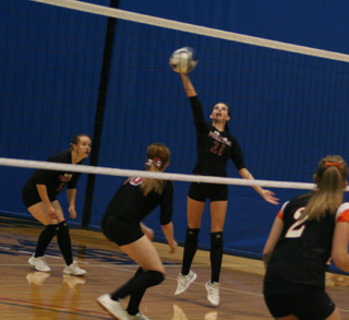 Sam Poxleitner spikes the ball against Troy. Also shown are Monica Lustig and Kayla Johnson.