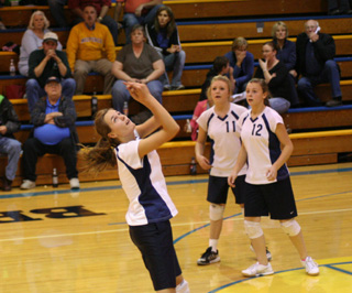 Savanah Prigge bumps the ball over the net in the District championship match against Nezperce. Watching are Cassidy Stubbers and Brooke Schumacher.