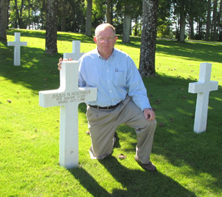 Father Jerry Funke with the grave marker for Julius H. Holthaus in Meuse-Argonne American Cemetery in Romagne, France. Holthaus was killed in action during World War I.