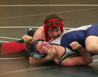 Garrett Schmidt puts his chin on a Lake City wrestler as he attempts to pull him down for the pin.