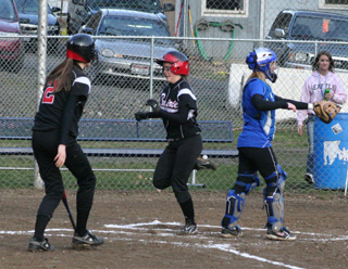 Megan Sigler scores the first run of the season in the first inning agaisnt Orofino. At left is Savanah Prigge.