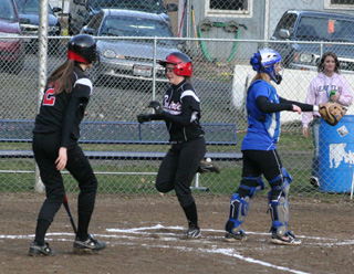Megan Sigler scores the first run of the season in the first inning agaisnt Orofino. At left is Savanah Prigge.