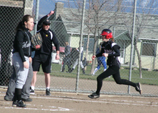 Coach Jeff Martin waves on Tanna Schlader as she turns third on a first inning homer against Highland.