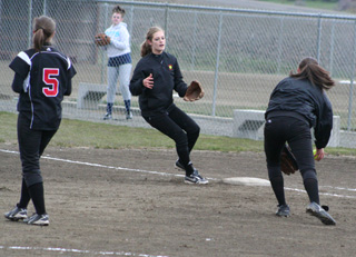 Meaghan Bruner is about to toss the ball to Tanna Schlader for a rare first baseman to second baseman putout at first against Grangeville. At left is pitcher Megan Sigler.