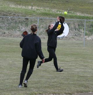 Monica Lustig catches a fly ball in centerfield as shortstop Leah Holthaus watches.
