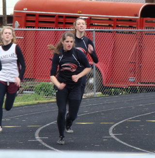 Shelby VonBargen gets started as Tyler Workman nears the end of her leg of the 4x100 relay and is about to hand off the baton. Photo by Kayla Raymond.