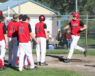 Devin Schmidt is greeted at home plate by teammates after the second of his two homers in his final high school game.