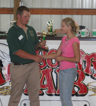 Sydney Tiede receives the trophy for top rabbit showman from 4-H Ambassador Frank Spencer. She was also grand champion showman for rabbits.