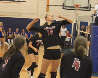 Tyler Workman winds up for a spike as Monica Lustig, 5, and Megan Sigler, 4, watch. Behind Workman is Tanna Schlader.