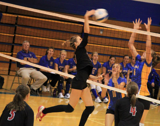 Leah Holthaus spikes the ball against Nezperce. In the foreground are Monica Lustig and Megan Sigler.