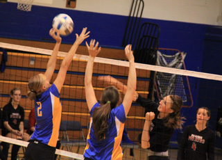 Tyler Workman slams a spike past Nezperce blockers as Megan Sigler looks on.