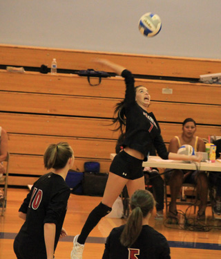 Sam Poxleitner is about to spike the ball against Lapwai. Watching are Leah Holthaus and Monica Lustig.