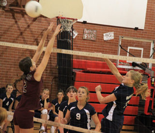 Summits Kayla Schumacher spikes the ball pasta Kamiah blocker. Watching are Nicole Frei and Brooke Schumacher.