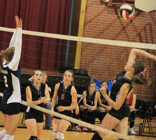 Tyler Workman goes for a kill against Grangeville as Megan Sigler, Monica Lustig and the Prairie bench look on.