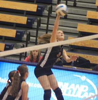 Tanna Schlader spikes the ball. Watching are MeShel Rad and Megan Sigler.