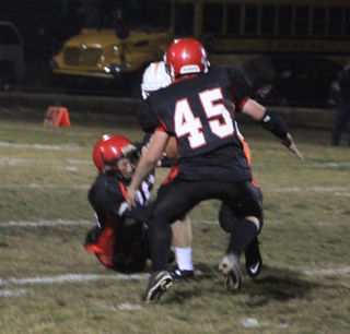 Torin Dalgliesh and Garrett Schmidt, 45, combine to tackle Troys quarterback for a big loss on fourth down that ended Troys first possession of the game.