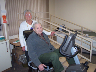Bill Estabrooks shows Mary Watson, RN that he can still ride the exercise bike.