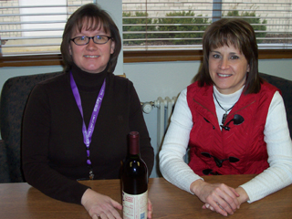 Leianne Everett and Debbie Schumacher showing off one of the bottles of wine which will part of the wine tree that will be auctioned off at the SMH Mardi Gras on February 25th.
