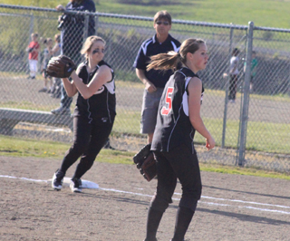 After taking a toss from Megan Sigler, right, at first for an out, first baseman Kendall Schumacher gets ready to throw home to complete a huge double play. Catcher MeShel Rad held on to the ball at the plate for the out despite a collision with the runner.