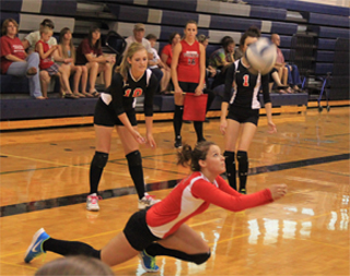 Stephanie Gimmeson digs up a serve as Tanna Schlader and Leah Holthaus watch.