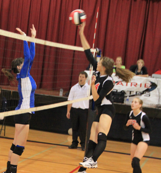Shelby VonBargen tries to guide her spike past a Genesee blocker as Hailey Danly looks on.