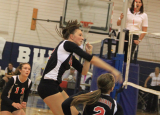 Tyler Workman smashes a spike against Kamiah as Krystin Uhlenkott and Hailey Danly watch.
