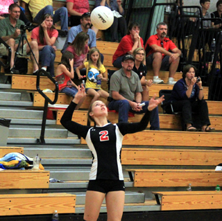 Hailey Danly serves against Clarkston at the Border Battle. You can see some of the Prairie fans in the stands behind her.