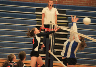 Krystin Uhlenkott pounds the ball past Genesees blockers in the league match at Genesee. Watching are Hailey Danly and Tyler Workman.