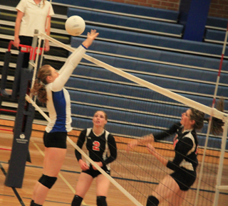 Shelby VonBargen spikes the ball against Genesee as Hailey Danly watches after setting the ball.