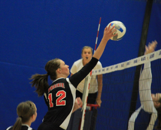Tyler Workman tips the ball past a Genesee block attempt during Distict. In the foreground is Hailey Danly.