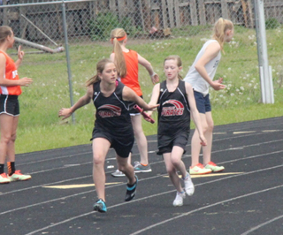 Laney Uhlenkott hands off to Kylie Tidwell in the 4x100 relay at the junior high meet at Kamiah Saturday.