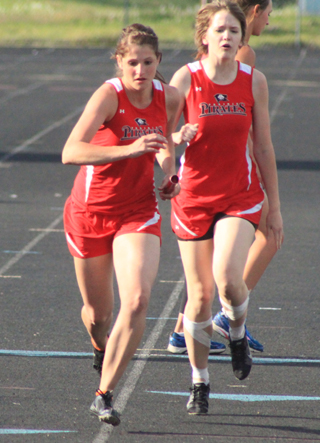 Shelby VonBargen, left, receives the baton for the third leg of the 4x400 relay from Claire Whitley. They qualified for state along with leadoff runner Keely Schmidt and anchor runner Krystin Uhlenkott.