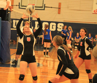 Hailey Danly sets the ball as Krystin Uhlenkott gets ready for the spike. At right is Natasha Gimmeson.