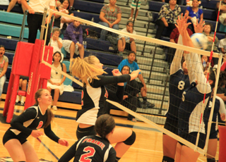 Kayla Schumacher powers a spike right past the Lapwai blockers. Also shown are Hailey Danly and Natasha Gimmeson.