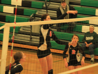 Kyndahl Ulmer, an in-season transfer from Kamiah, spikes the ball at Potlatch. Also shown are Hailey Danly, left, and Natasha Gimmeson, right. Prairie bus driver Rick Johnson is shown in the background.