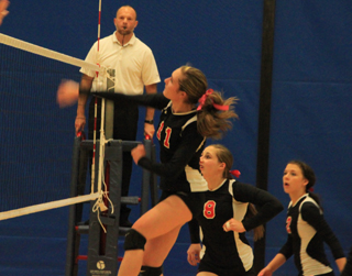 Krystin Uhlenkott spikes the ball against Troy at District. Also shown are Hailey Danly and Natasha Gimmeson.
