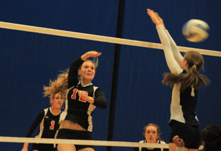 Kayla Schumacher spikes the ball against Lapwai. Also shown are Leah Holthaus and Krystin Uhlenkott.