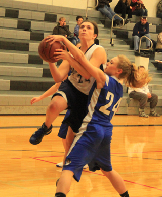 Megan Rehder gets checked by an Orofino player as she goes up for a shot.