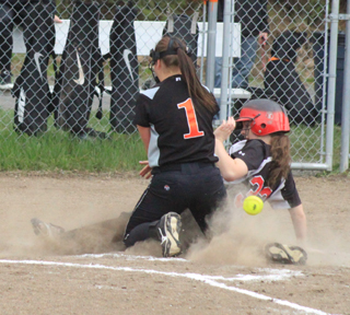 Faith Uhlenkott is safe at home after scoring on a wild pitch as the ball gets away from Troys pitcher on an attempted tag.