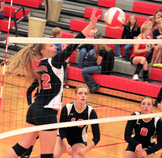 Kayla Schumacher tips the ball over against C.V. as Holli Uhlorn and Hailey Danly watch and get ready for a possible return.