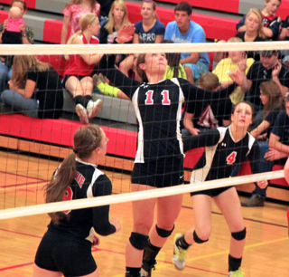 Krystin Uhlenkott goes for a spike at C.V. as Hailey Danly, left, and Shayla VonBargen watch.