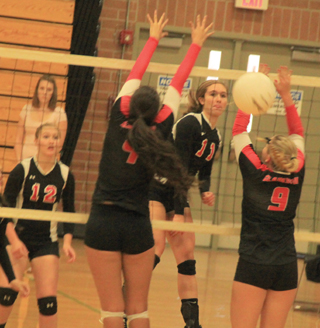 Krystin Uhlenkott puts a spike between two Clarkston blockers at the Border Battle in Pomeroy. At left is Kayla Schumacher.