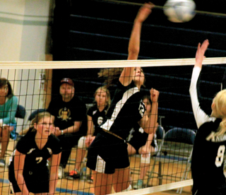 Megan Seubert spikes the ball at Logos. At left is Lucy Osborne.