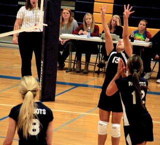Summits Rachel Waters sets the ball at Logos as  Megan Seubert, 12 gets ready for the kill while Lauren Stubbers watches.