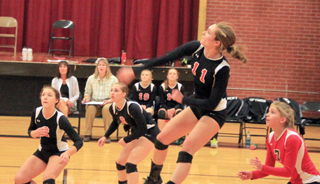 Krystin Uhlenkott pounds the ball over against Troy from the back row. Also shown are Natasha Gimmeson and Hailey Danly.